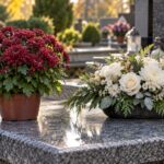 Żywa bordowa chryzantema i jasna kompozycja sztucznych kwiatów ustawione obok siebie na nagrobku